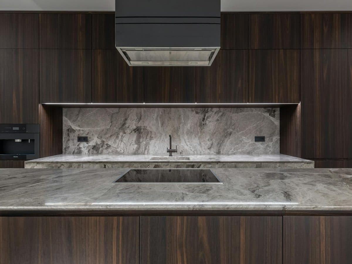 Modern kitchen with dark walnut cabinets and a gray quartzite countertop with bold natural movement and a matching slab backsplash